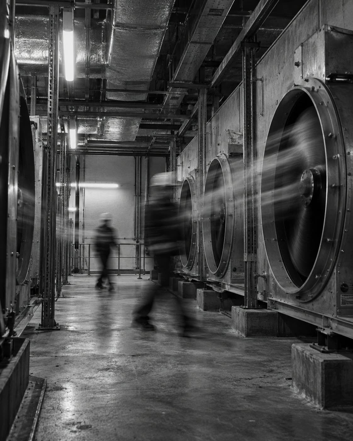 Reference photograph: spinning AHU fans in a plant corridor with a technician blurred in motion