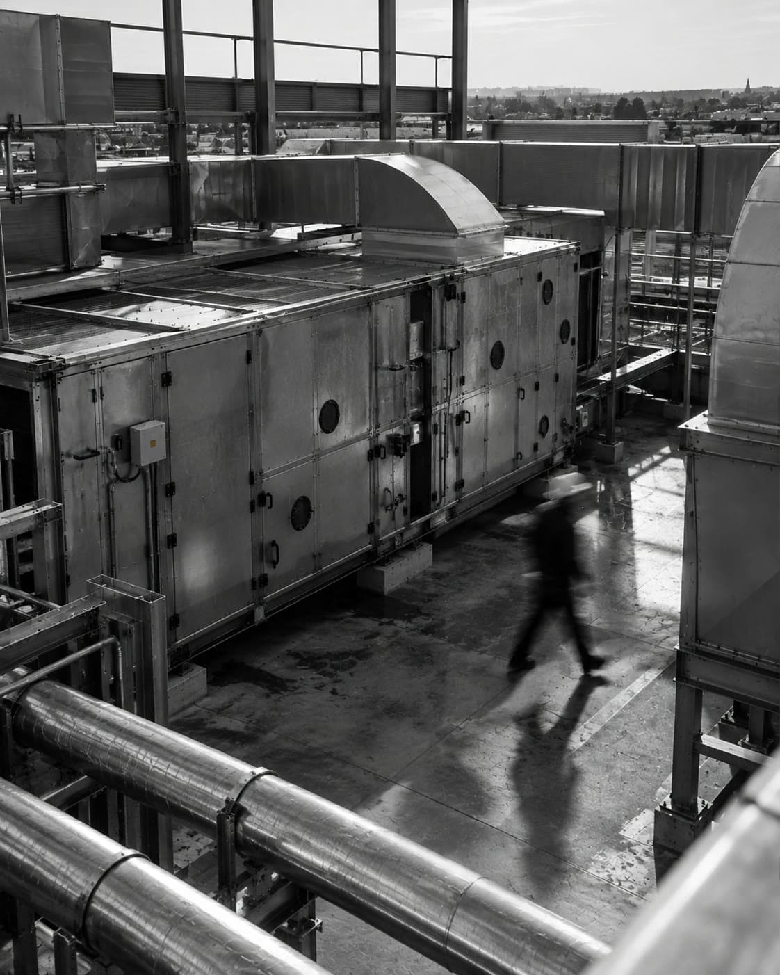Reference photograph: rooftop AHU plant against a city skyline, with a technician blurred in motion
